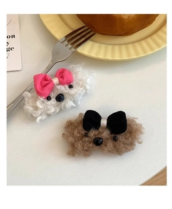 Detail of plush puppy hair clips in white and brown with colorful bows on a white surface