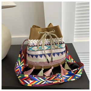 Detail of canvas bucket bag featuring ethnic embroidery, tassels, and a geometric strap