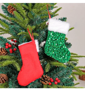 Detail of red felt and green sequined Christmas stockings hanging on a festive pine tree
