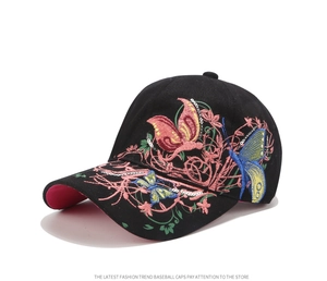 Dettaglio del ricamo farfalla con paillettes e motivi floreali sul cappellino