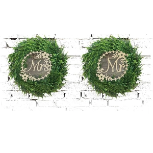 Detail of Mr and Mrs wooden wedding chair signs with green foliage wreaths and floral accents