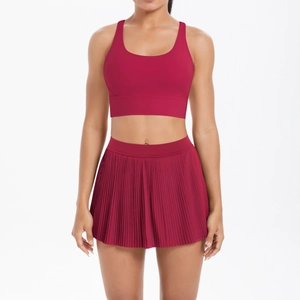 Front view of burgundy yoga sports bra and pleated tennis skirt set on white background