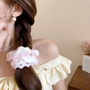 Vue détaillée d'un chouchou en dentelle à fleurs roses sur une tresse