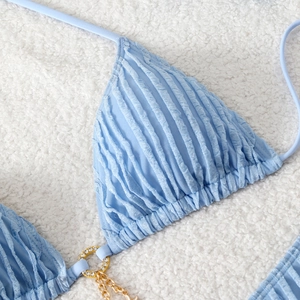 Close-up of light blue textured bikini top featuring gold ring with crystal and chain