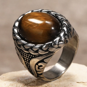 Macro view of vintage stainless steel ring with oval tiger eye stone and braided texture