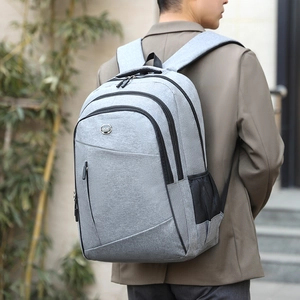 Gray business casual oxford backpack with multi-compartment storage worn by male model