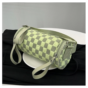 Detail of checkered barrel crossbody bag showing green bubble fabric and wide strap