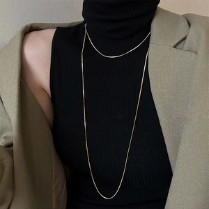 Close-up of golden double-layer thin necklace on a model wearing a black turtleneck