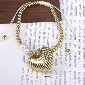 Macro detail of hand-woven bracelet with 25mm gold heart pendant and metallic beads