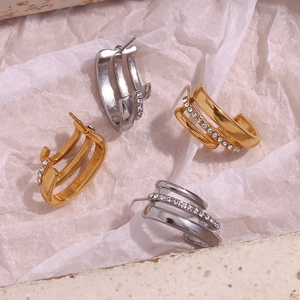 Detail view of gold and silver layered C-shape stud earrings with sparkling rhinestones