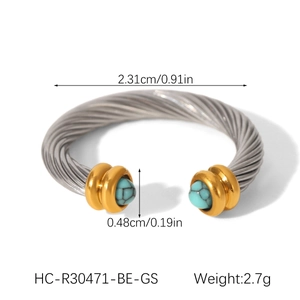 Détail d'une bague torsadée en acier inoxydable avec perles turquoise et touches dorées