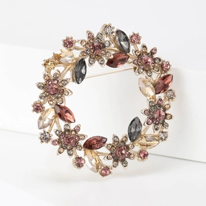 Close-up of floral wreath brooch with colorful crystals and rhinestones on gold base