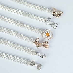 Detailed macro view of various pearl waist chains with golden and silver butterfly buckles