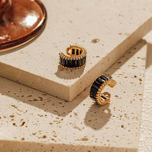 Detail of C-shaped ear cuff with black faceted stones and gold beaded edges on stone