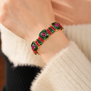 Detail shot of vintage green enamel square bracelet with red beads and golden metal accents