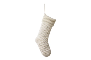 Close-up of cream white knitted Christmas stocking featuring detailed cable knit patterns