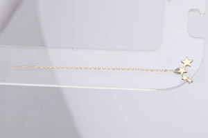 Close-up of gold ear threaders featuring a gradient of three star-shaped zircon stones