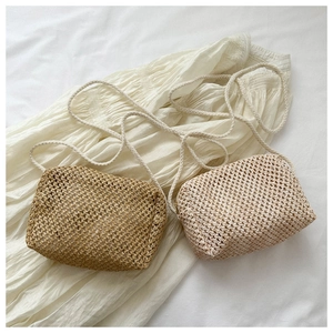 Detail of hand-woven straw crossbody bags in light brown and cream with zipper closure