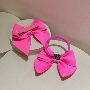 Neon pink handmade ribbon bow hair clip and elastic hair tie set on a white stand