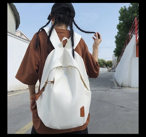 Minimalist white canvas backpack for students shown in an outdoor lifestyle setting