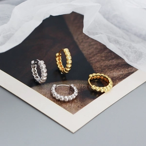 Macro detail of gold and silver beaded hoop earrings with a textured bubble design