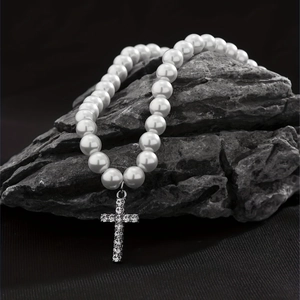 Detailed view of pearl necklace with rhinestone cross pendant on stone surface