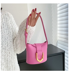 Detail of pink leather handbag with gold D-ring hardware and long shoulder strap