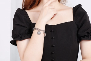 Detail of silver double-layer sun pendant bracelet on model wrist with black sleeve