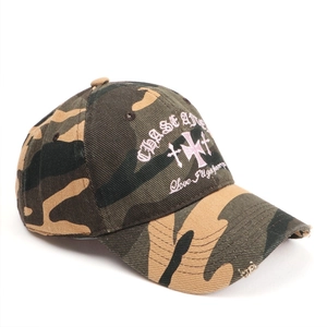 Détail d'une casquette camouflage vintage avec broderie croix rose et bordure usée.