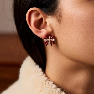Detail of red flower stud earrings with sparkling crystal center on model's ear