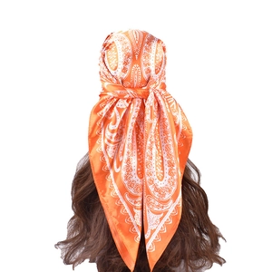 Orange paisley satin square scarf shown as a stylish headwrap on a brunette model