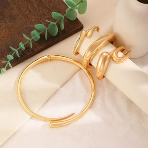 Minimalist gold metal jewelry set with choker and rings on a white display stand