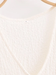 Close-up of V-neckline on waffle knit top with size S label in soft lighting