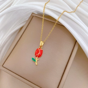Detail shot of a golden necklace featuring a vibrant red oil-dripped tulip pendant