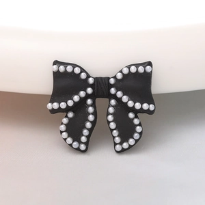 Detail of black bow ornament with white pearl border for DIY crafts and accessories