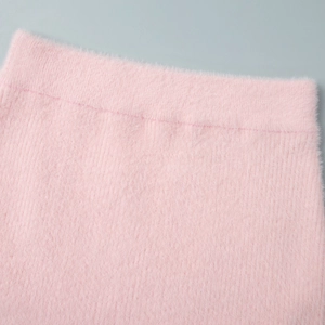 Close-up of soft pink faux fur texture and stitching details of the knit mini dress
