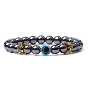 Detailed macro view of hematite beaded bracelet with evil eye and gold crown charms