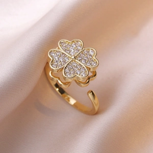 Anello rotante a quadrifoglio in oro con zirconi bianchi su sfondo di seta champagne