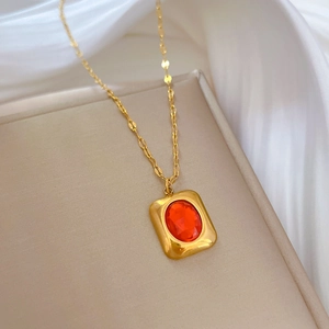 Close-up of a vintage square gold pendant with a ruby gemstone on a silk background