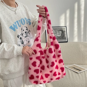 Detailed texture of pink plush heart tote bag with soft faux fur and red heart patterns