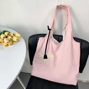 Pink canvas tote bag with pleated texture and white flower charm on a black chair