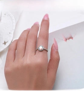 Close-up of S925 sterling silver halo ring with round opal and zircons on finger