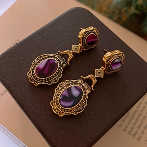 Detailed macro view of vintage gold earrings with purple gemstone cabochons