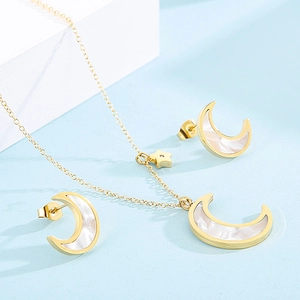 Detail of star and moon jewelry set with white pearl inlay on a soft blue background
