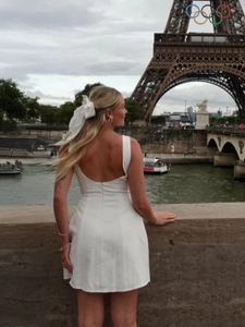Chic backless white mini dress with bow accessories against the Eiffel Tower backdrop