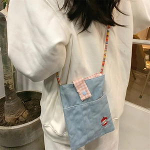 Detail of denim crossbody phone bag with apple embroidery and colorful beaded strap