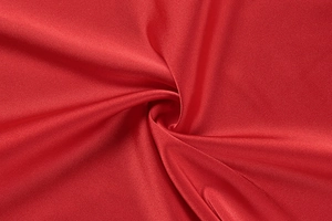 Detail shot of luxury dark red satin fabric with elegant silk texture and glossy drape