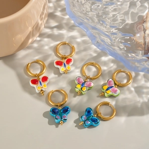Close-up of three pairs of colorful enamel butterfly drop earrings on grey surface