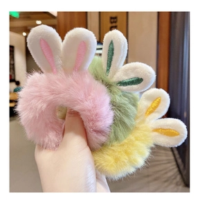 Detail of plush rabbit ear hair ties in pastel pink, green, and yellow with embroidery