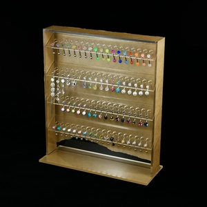 Four-tier clear acrylic display stand showcasing colorful belly and tongue rings on black background